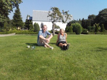 Ungt par sidder på græsplænen ved Vrads kirke